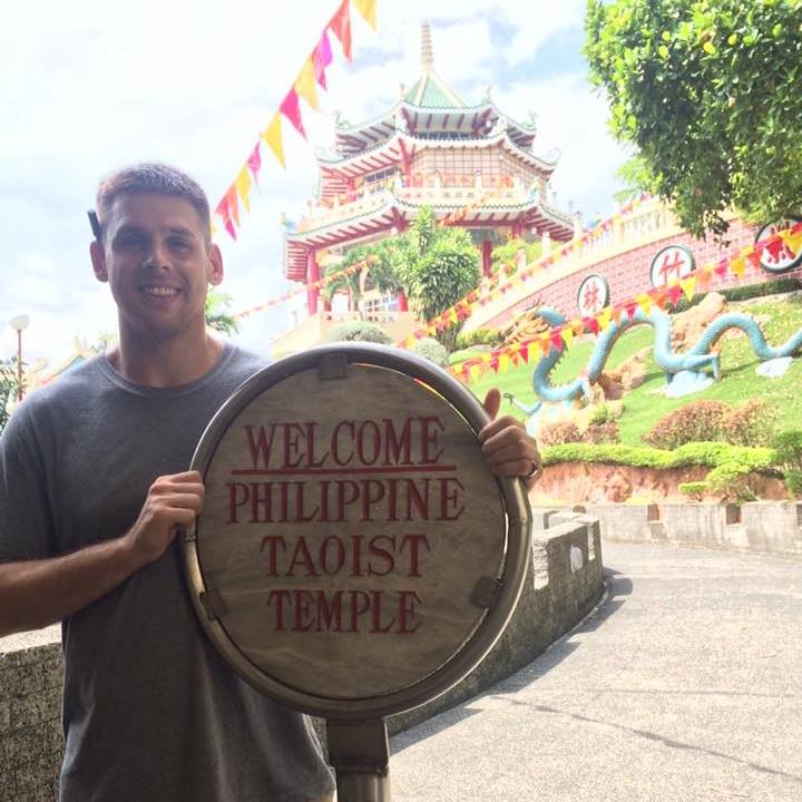 Person posing with a sign at a tourist attraction